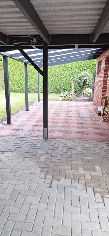 Gepflasterte und überdachte Terrasse mit Blick auf den Garten